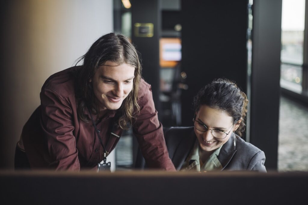 A male and female tech professional smile as they collaborate on a work project.