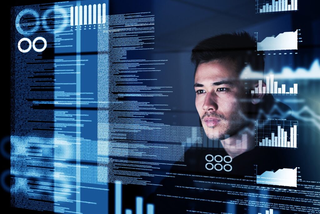 A cybersecurity analyst's face is reflected in a monitor screen full of text, graphs, and graphics.
