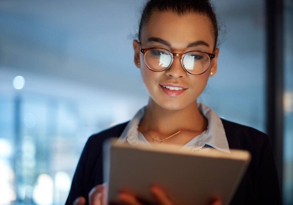 A woman in business attire uses a tablet.